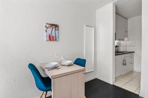 kuchnia ze stołem i 2 niebieskimi krzesłami w obiekcie City Center-Twin Bed-Coffee-Workplace-Washer w mieście Winterthur