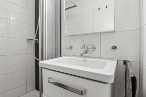 La salle de bains est pourvue d'un lavabo blanc et d'une douche. dans l'établissement City Center-Twin Bed-Coffee-Workplace-Washer, à Winterthour