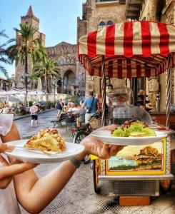 duas pessoas a segurar pratos de comida num carrinho de comida em Meravigghia Suites Cefalù em Cefalù