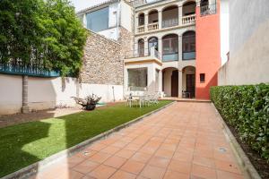 a courtyard of a house with a patio and grass at ca n'Arago, edificio modernista del arquitecto Rafael Maso in Santa Coloma de Farners