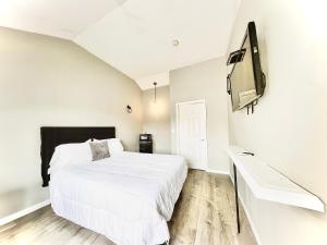 Schlafzimmer mit einem Bett und einem Flachbild-TV in der Unterkunft Penn Lodge Hotel & Suites Philadelphia - Bensalem in Bensalem