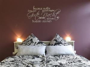 a bedroom with a bed with pillows and words on the wall at Zeit zu Zweit an der Wieke mit Kamin in Großefehn 