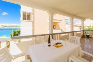 a white table with wine glasses on a balcony at Bepo Apartments at beach in Metajna