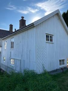 a white building with a chimney on top of it at Huset i hagen in Mandal