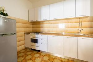 a kitchen with white cabinets and a stainless steel refrigerator at Bepo Apartments at beach in Metajna