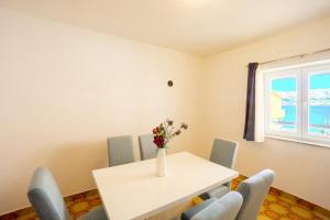 a dining room with a table and chairs and a vase with flowers at Bepo Apartments at beach in Metajna