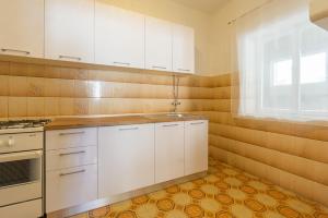 a kitchen with white cabinets and a sink and a window at Bepo Apartments at beach in Metajna