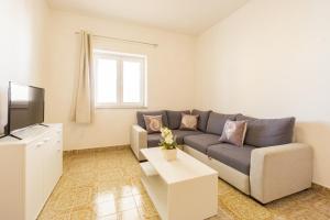 a living room with a couch and a tv at Bepo Apartments at beach in Metajna