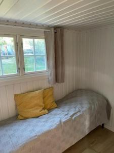 a small bed in a room with two windows at Huset i hagen in Mandal