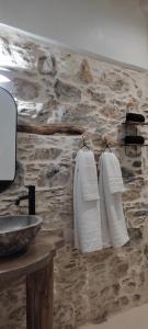 a bathroom with white towels hanging on a stone wall at ClockWise Earthy Vibe House in Apano Chora in Ano Syros +37 photos