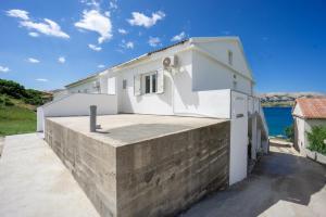 een wit huis met een betonnen steunmuur bij Bepo Apartments at beach in Metajna