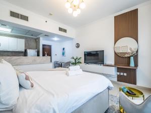um quarto com uma grande cama branca e uma televisão em Delightful Studio with Balcony - Burj Al Nujoom em Dubai