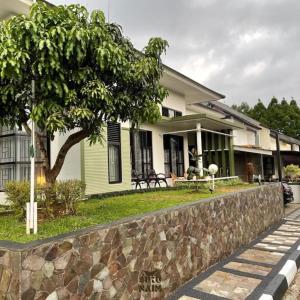 a house with a stone wall in front of it at Villa Siku Naim, Sukabumi in Sukabumi
