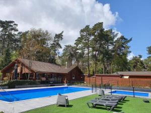 una piscina con tumbonas y una casa en Vakantiehuis Veluws Genieten met whirlpool en sauna, en Doornspijk