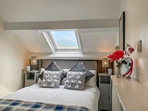 a bedroom with a bed with a window above it at Hyfrydle Cottage in Pen-y-groes