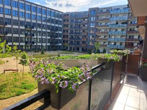 un balcón con flores y edificios en el fondo en Tabáň Halifax apartment - city center & free parking, en Nitra