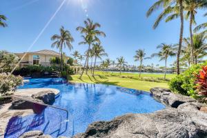 a swimming pool with palm trees and a house at Waikoloa Fairway Villas #L22 in Waikoloa