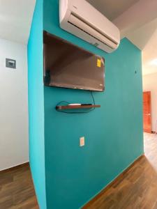 Cette chambre est dotée d'un mur bleu et d'un réfrigérateur. dans l'établissement Casa Suites Minizoo, à Puerto Escondido