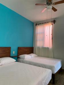 um quarto com 2 camas e uma ventoinha de tecto em Casa Suites Minizoo em Puerto Escondido