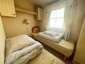 a small bedroom with two beds and a window at 4 Berth Nearby Hunstanton Beach In Norfolk Ref 13018l in Hunstanton
