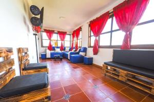 a living room with blue chairs and red curtains at cabaña villa rica in Ráquira