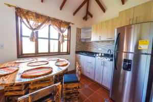 a kitchen with a table and a stainless steel refrigerator at cabaña villa rica in Ráquira