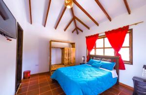 1 dormitorio con cama azul y espejo en cabaña villa rica, en Ráquira