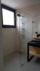 La salle de bains est pourvue d'une douche en verre et d'une fenêtre. dans l'établissement Maison Luxueuse à Essaouira, à Essaouira