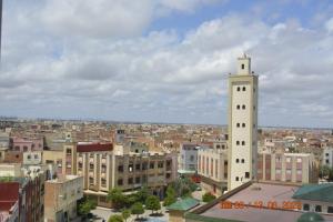 Blick auf eine Stadt mit einem hohen weißen Turm in der Unterkunft FEKRI HOTEL in Meknès