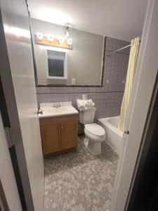 a bathroom with a toilet and a sink and a tub at Vacationland Inn & Suites in Brewer