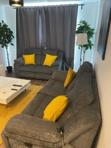 a living room with a couch and yellow pillows at Defining Luxury, Comfort& Class2 in Barking