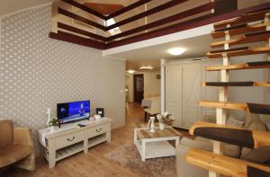 a living room with a television and a living room with a ladder at Gyulai idill apartman in Gyula