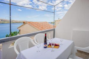 a table with glasses and a bottle of wine on a balcony at Bepo Apartments at beach in Metajna