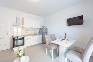 a kitchen and dining room with a white table and chairs at Bepo Apartments at beach in Metajna