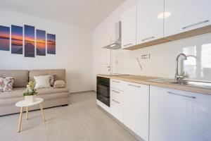 a kitchen with white cabinets and a couch at Bepo Apartments at beach in Metajna