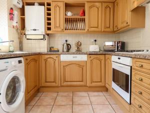 eine Küche mit Holzschränken, einer Waschmaschine und einem Trockner in der Unterkunft Aln Cottage Alnwick in Alnwick