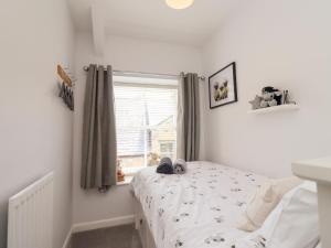 ein weißes Schlafzimmer mit einem Bett und einem Fenster in der Unterkunft Aln Cottage Alnwick in Alnwick