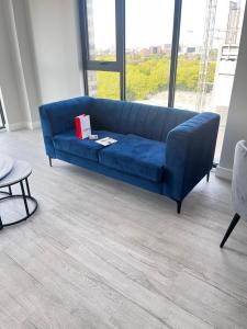 ロンドンにあるExecutive Luxury staysの大きな窓付きの客室で、青いソファが備わります。