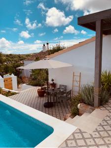 un patio con mesa y sombrilla junto a la piscina en Casa na Colina : The Cottage and The Long House, en São Brás de Alportel