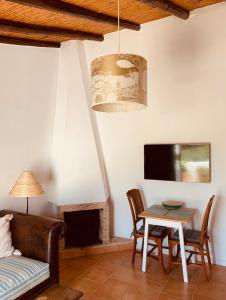 sala de estar con sofá, mesa y TV en Casa na Colina : The Cottage and The Long House, en São Brás de Alportel