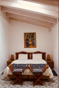 a bedroom with a large bed with two chairs at Casa na Colina : The Cottage and The Long House in São Brás de Alportel