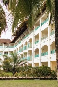 a large white building with palm trees in front of it at Sauipe Resorts Ala Mar - All Inclusive in Costa do Sauipe