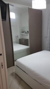 een slaapkamer met een spiegel en 2 bedden bij Appartamento incantevole con uso piscina e spa in Magliolo