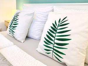 dos almohadas blancas con una hoja de palmera verde pintada en ellas en Moderne Ferienwohnung mit bodentiefer Dusche, Waschmaschine und Küche - "Hoffi", en Leipzig