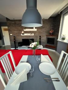 a dining room with a table with white chairs and a red couch at Apartament Morski z ogródkiem in Rumia