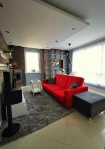 a living room with a red couch and a table at Apartament Morski z ogródkiem in Rumia