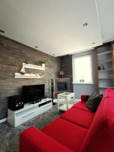 a living room with a red couch and a tv at Apartament Morski z ogródkiem in Rumia