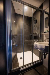 a glass shower in a bathroom with a sink at Hotel Auberge Nassau in Eindhoven