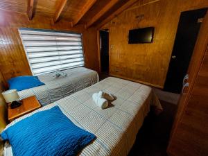a room with two beds and a television in a cabin at Hotel Gran Luna in Puerto Montt
