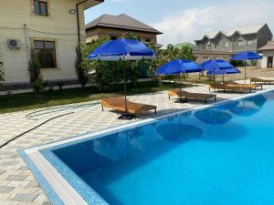 a swimming pool with blue umbrellas and lounge chairs and a pool at GREEN APPLE GUEST House in Tashkent +4 photos
